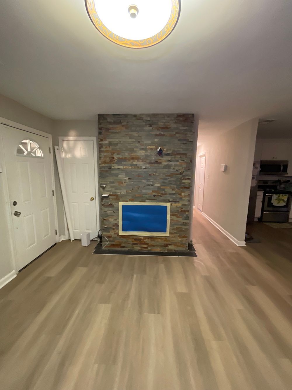 A living room with hardwood floors and a stone fireplace.
