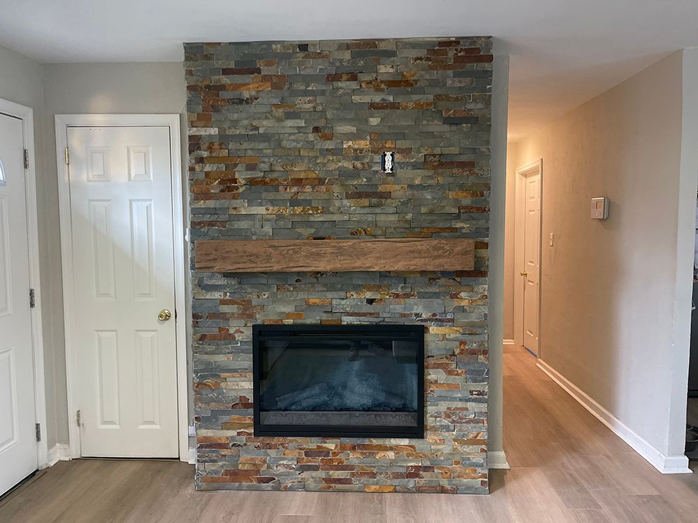 A living room with a stone fireplace and a wooden mantle.