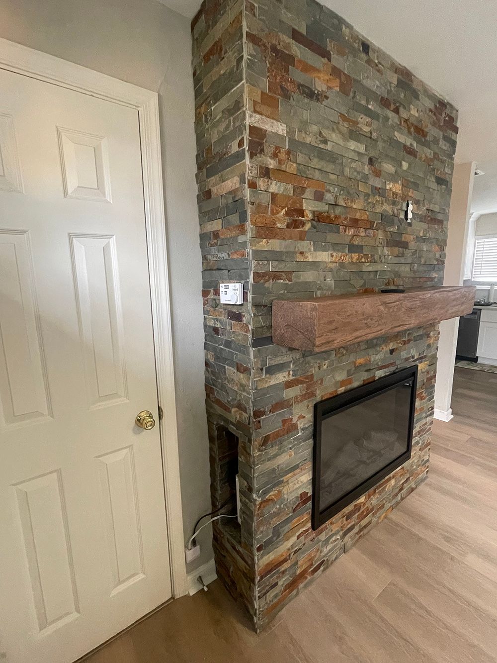 There is a fireplace in the middle of the room next to a door.