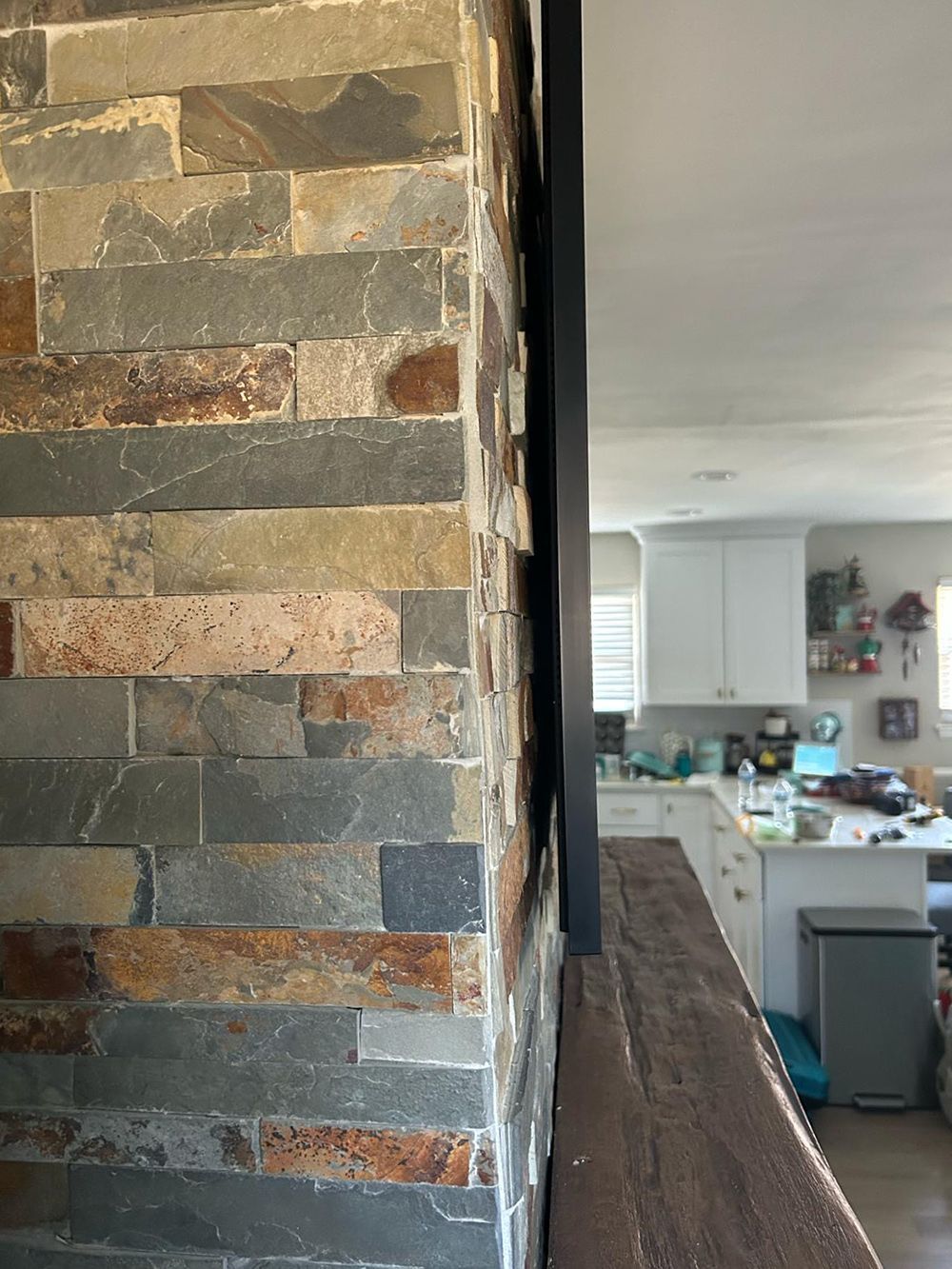 A kitchen with a stone wall and a wooden counter top.