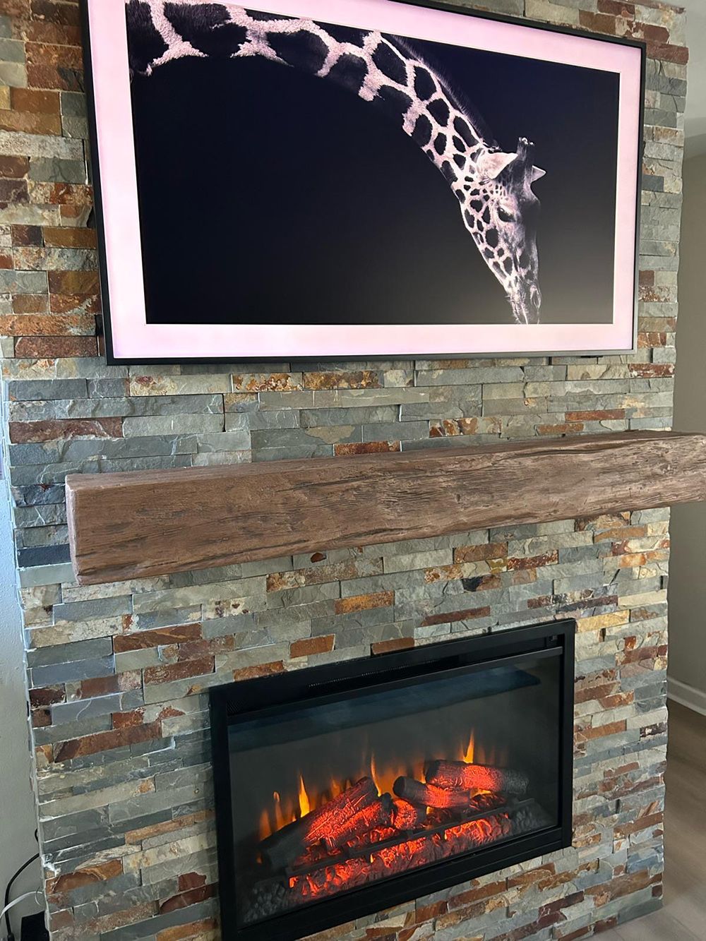 A fireplace with a picture of a giraffe on the wall above it.