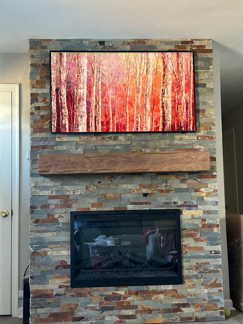 A fireplace with a painting on the wall above it.