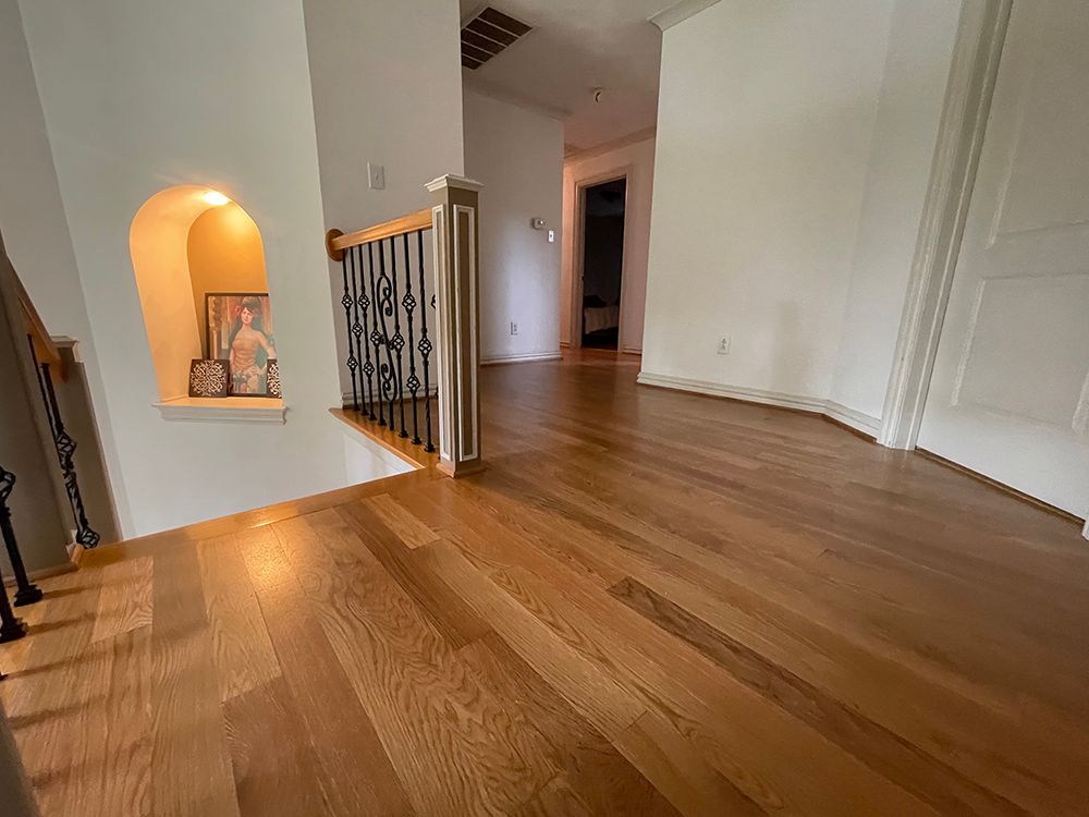 A hallway with hardwood floors and stairs in a house.