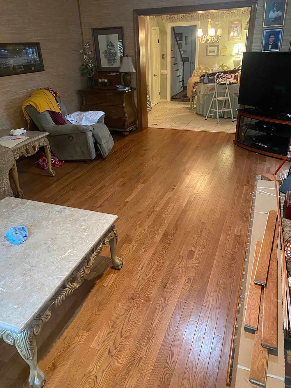 A living room with hardwood floors , a coffee table , chairs , and a television.