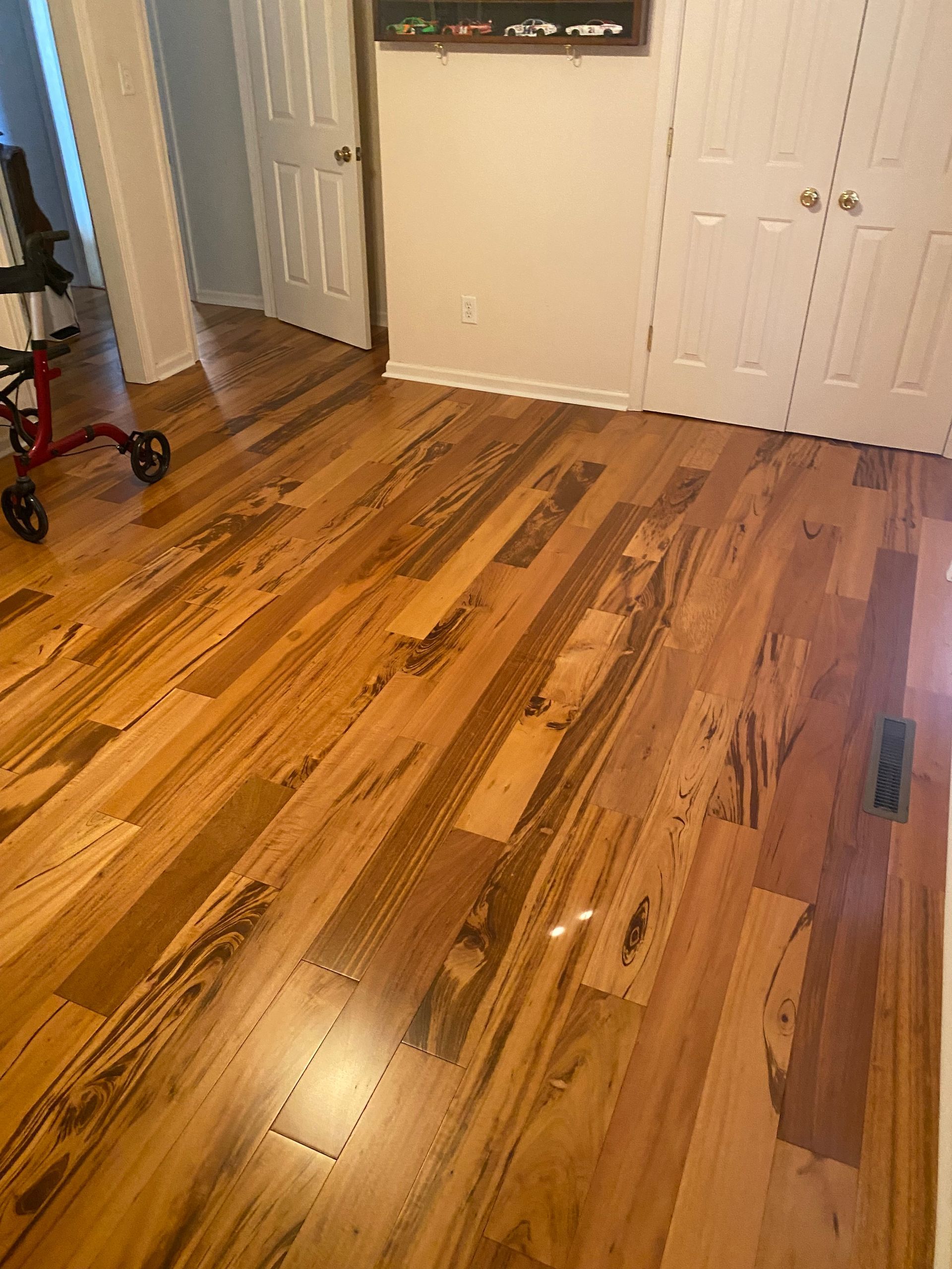 A wooden floor in a room with a walker in the background.