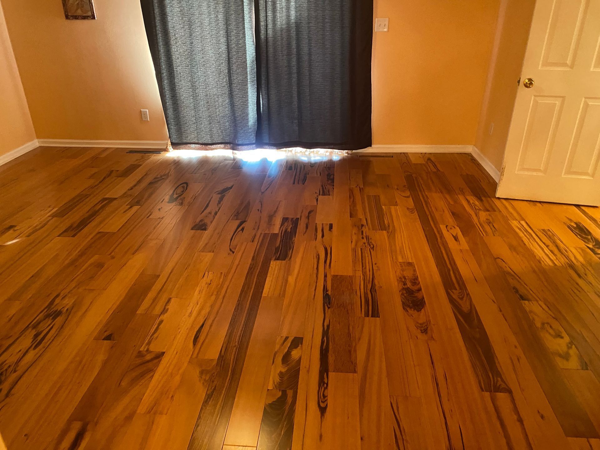 A bedroom with hardwood floors and a sliding glass door.