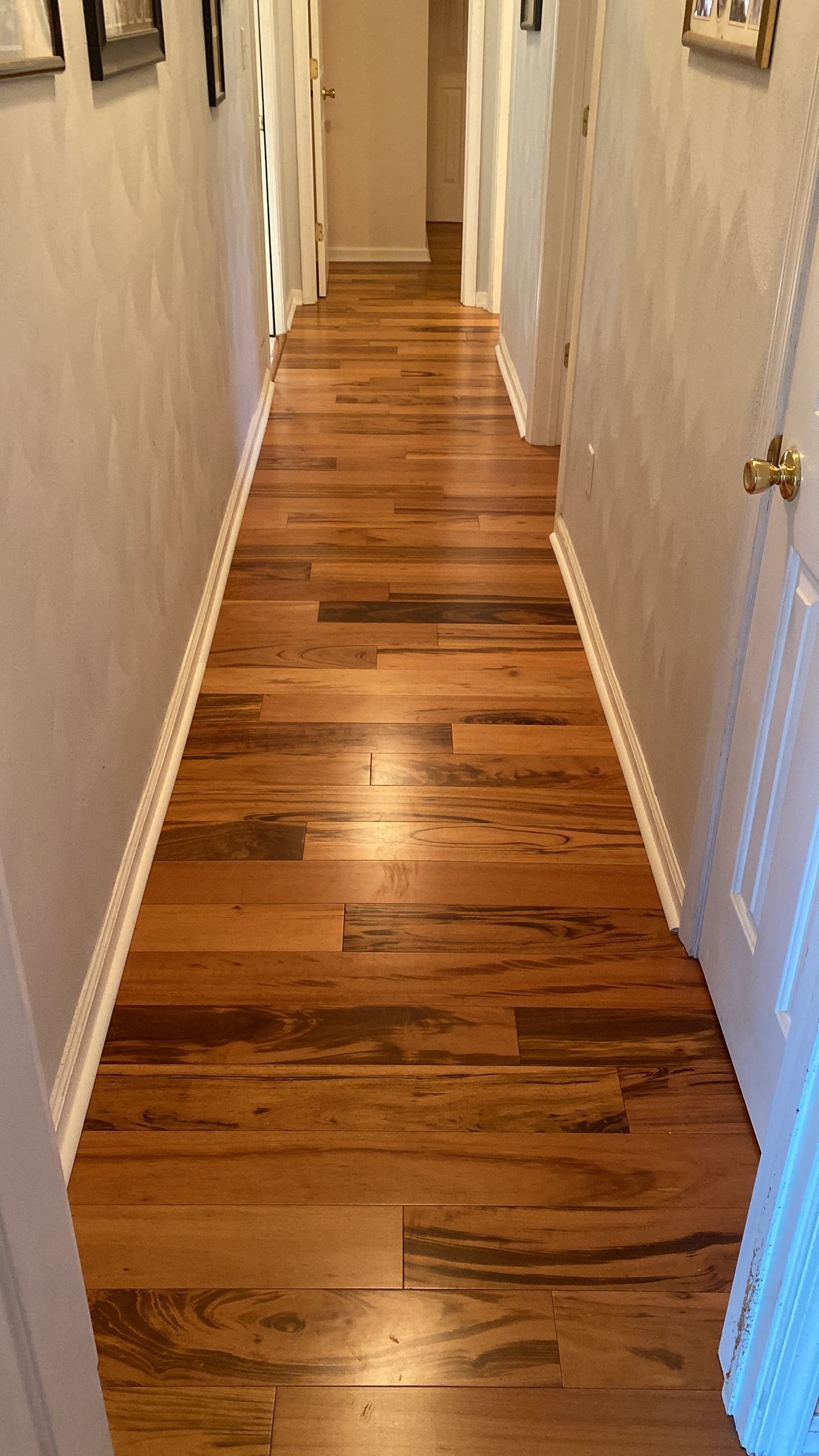 A long hallway with hardwood floors in a house.