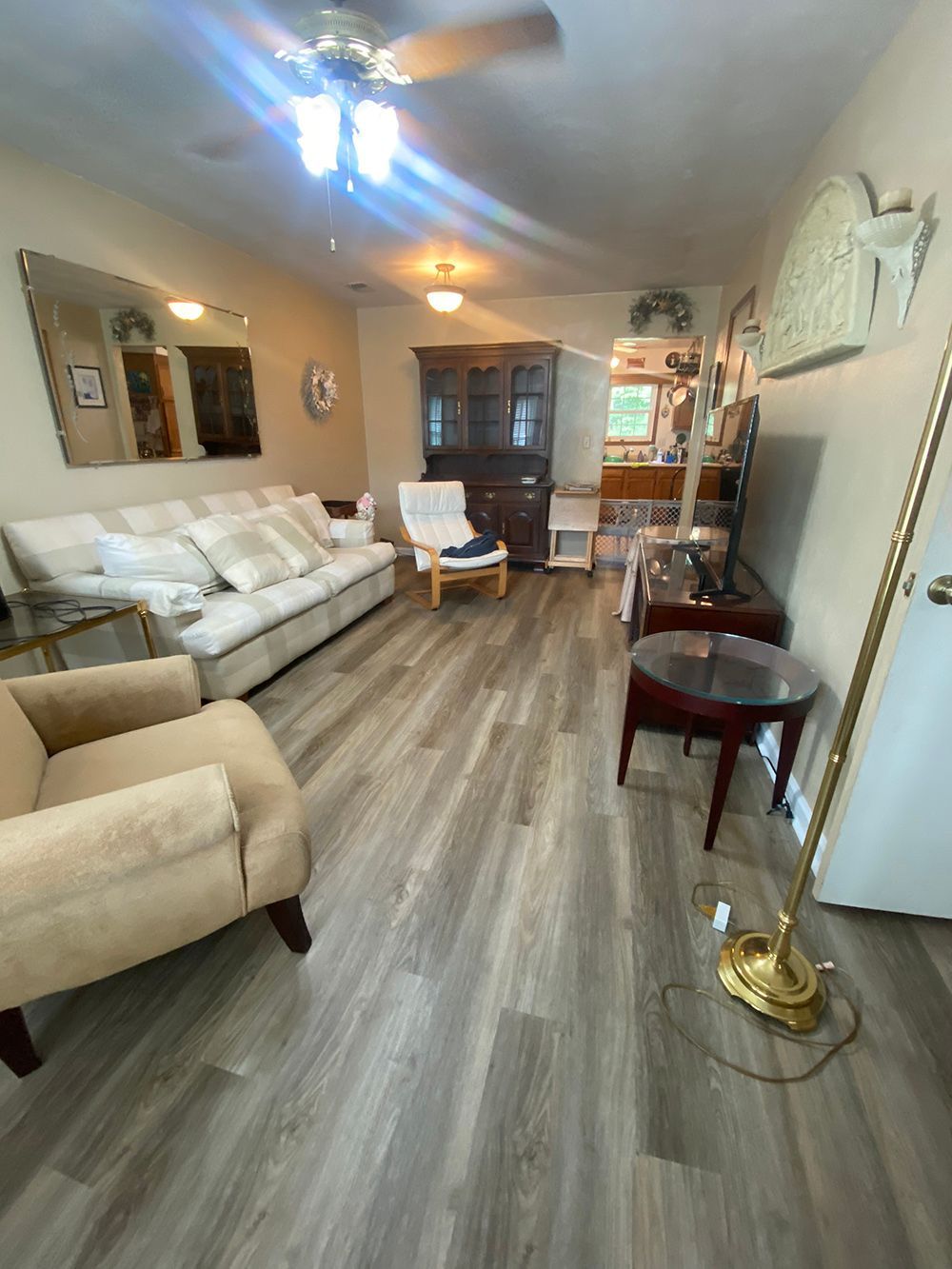 A living room with a couch , chair , table and ceiling fan.