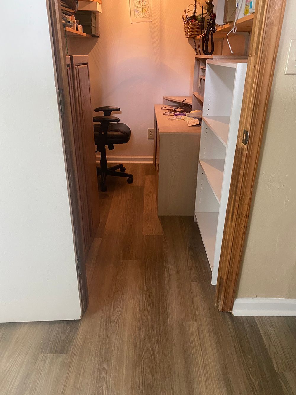 A hallway with hardwood floors and a desk and chair.