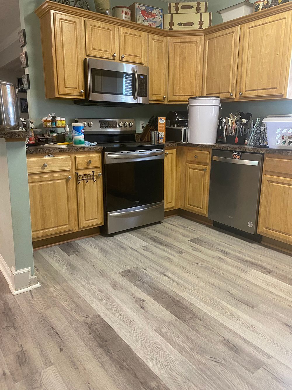 A kitchen with wooden cabinets , stainless steel appliances , a stove , microwave , and dishwasher.