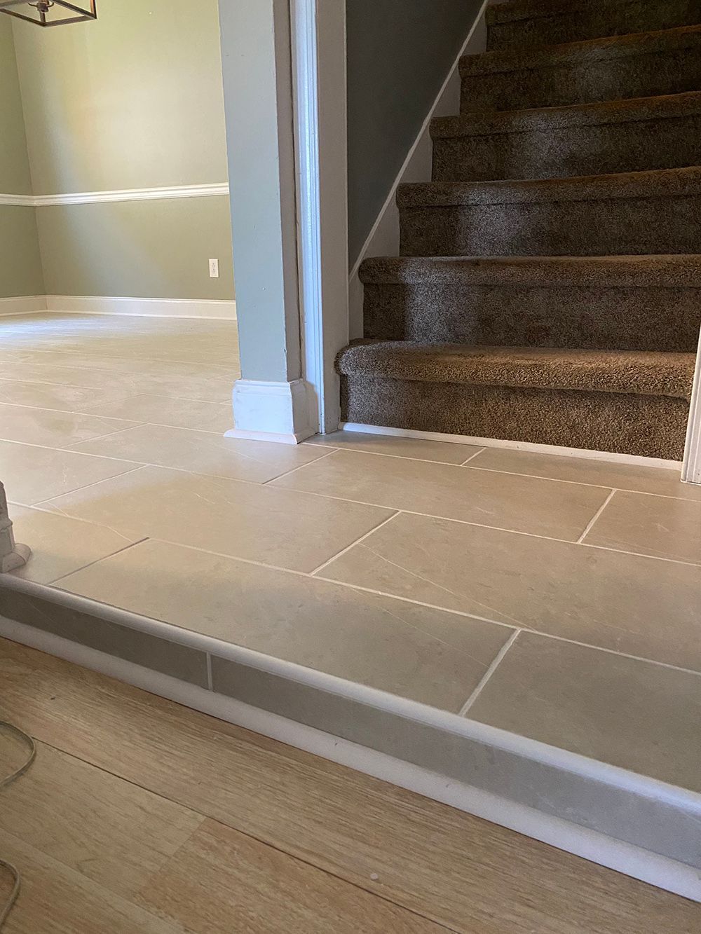 A staircase with carpeted steps and a tiled floor in a house.