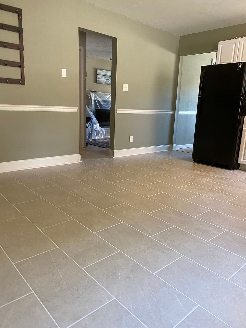 A living room with a tiled floor and a refrigerator.