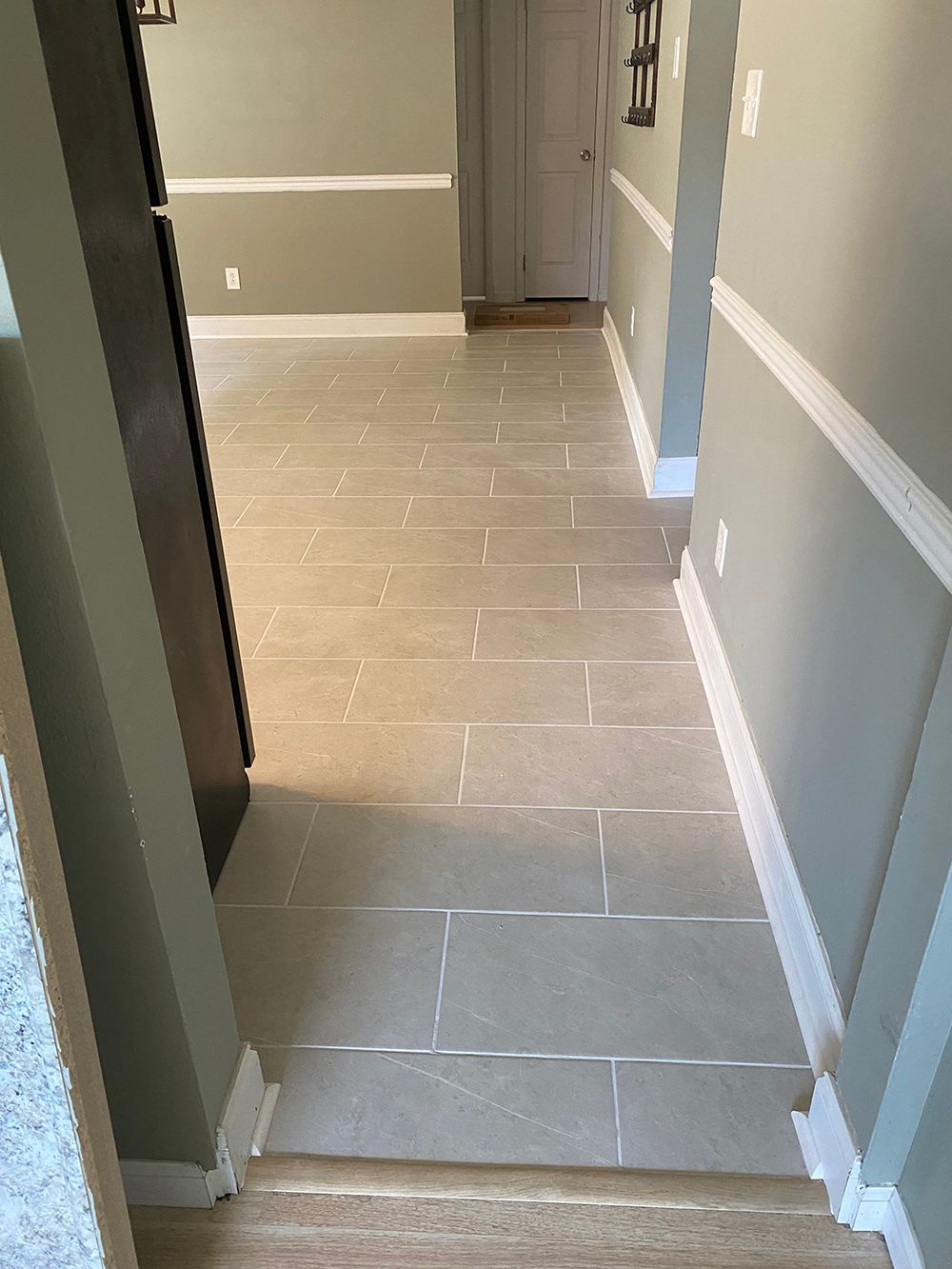 A hallway with tile floors and stairs leading to a living room.