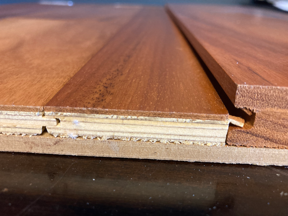 A close up of a wooden cutting board on a wooden floor.