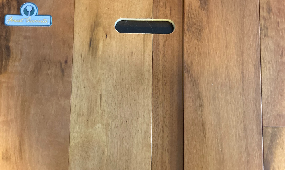 A close up of a wooden cutting board on a wooden floor.