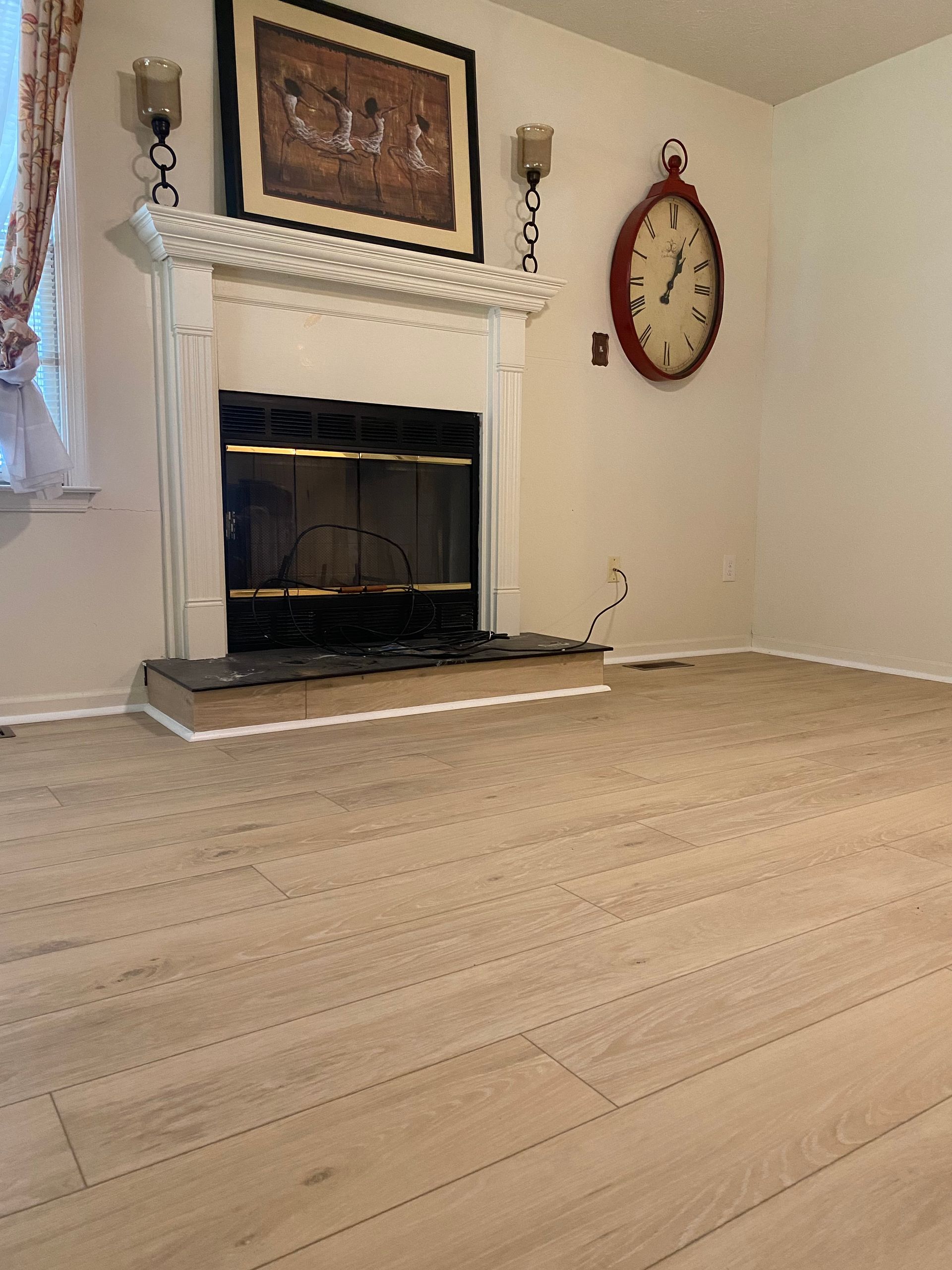 A living room with a fireplace and a clock on the wall.