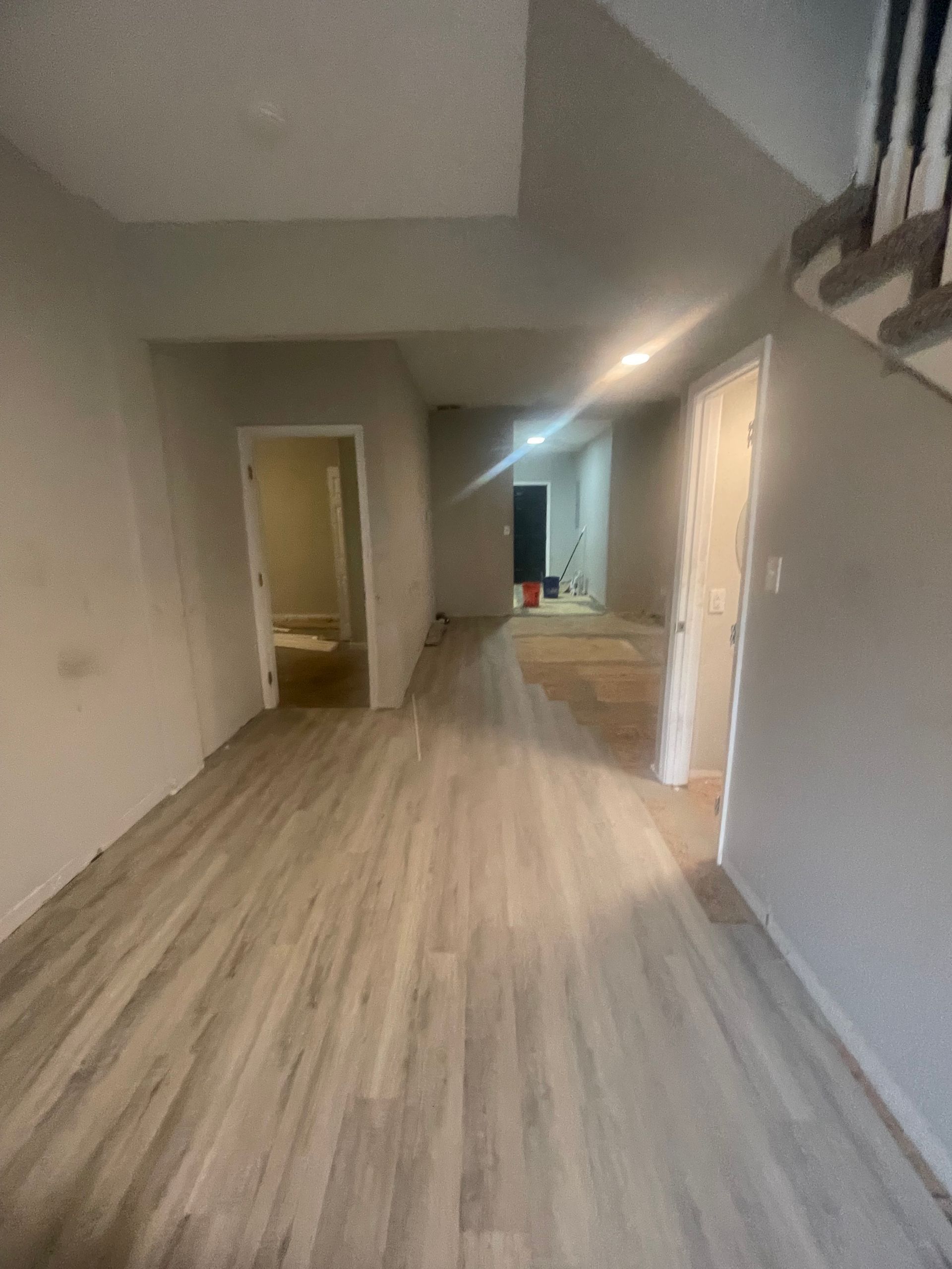 A hallway with hardwood floors and a staircase in a house.