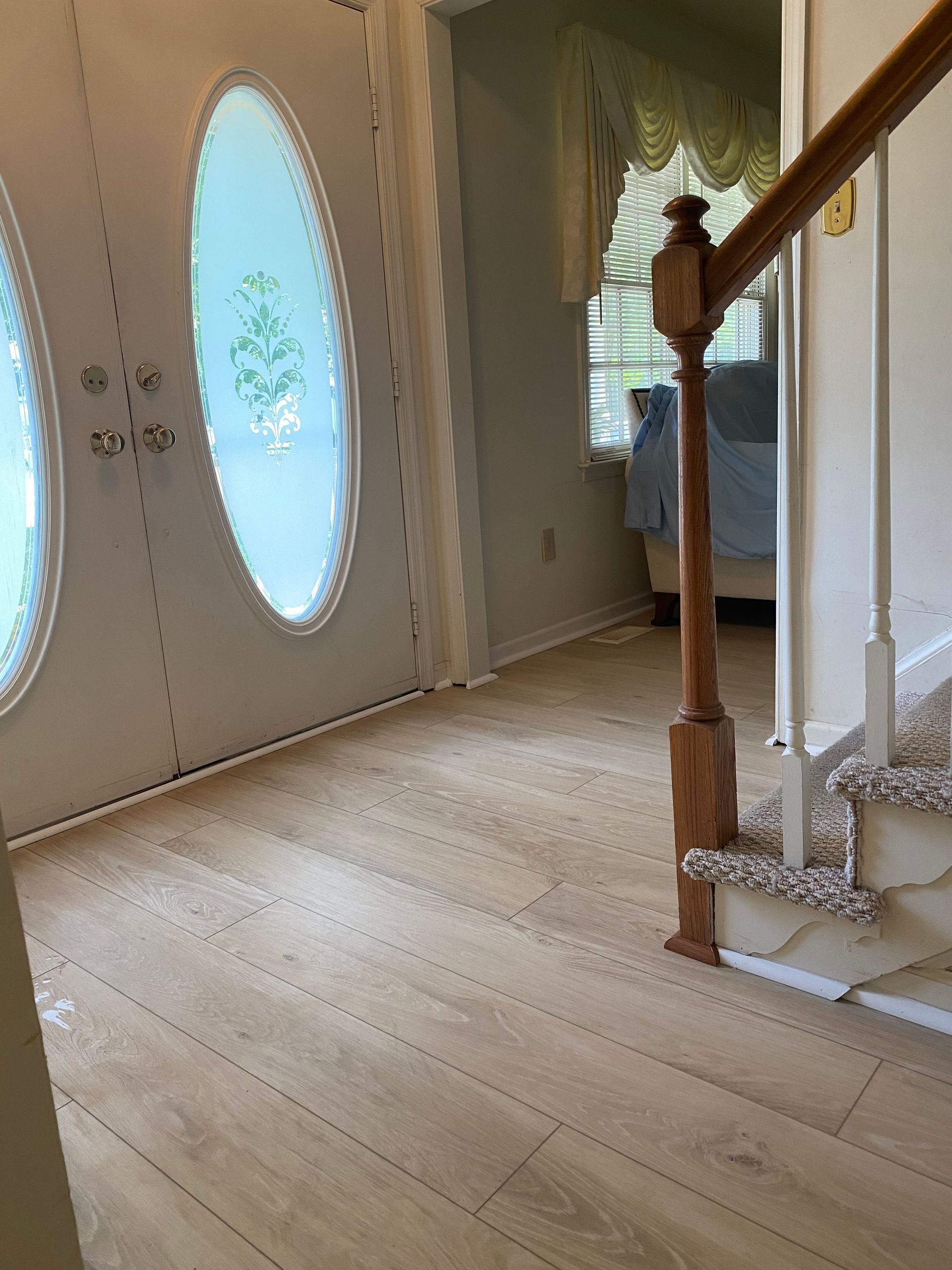 A hallway with stairs and a door with oval windows.