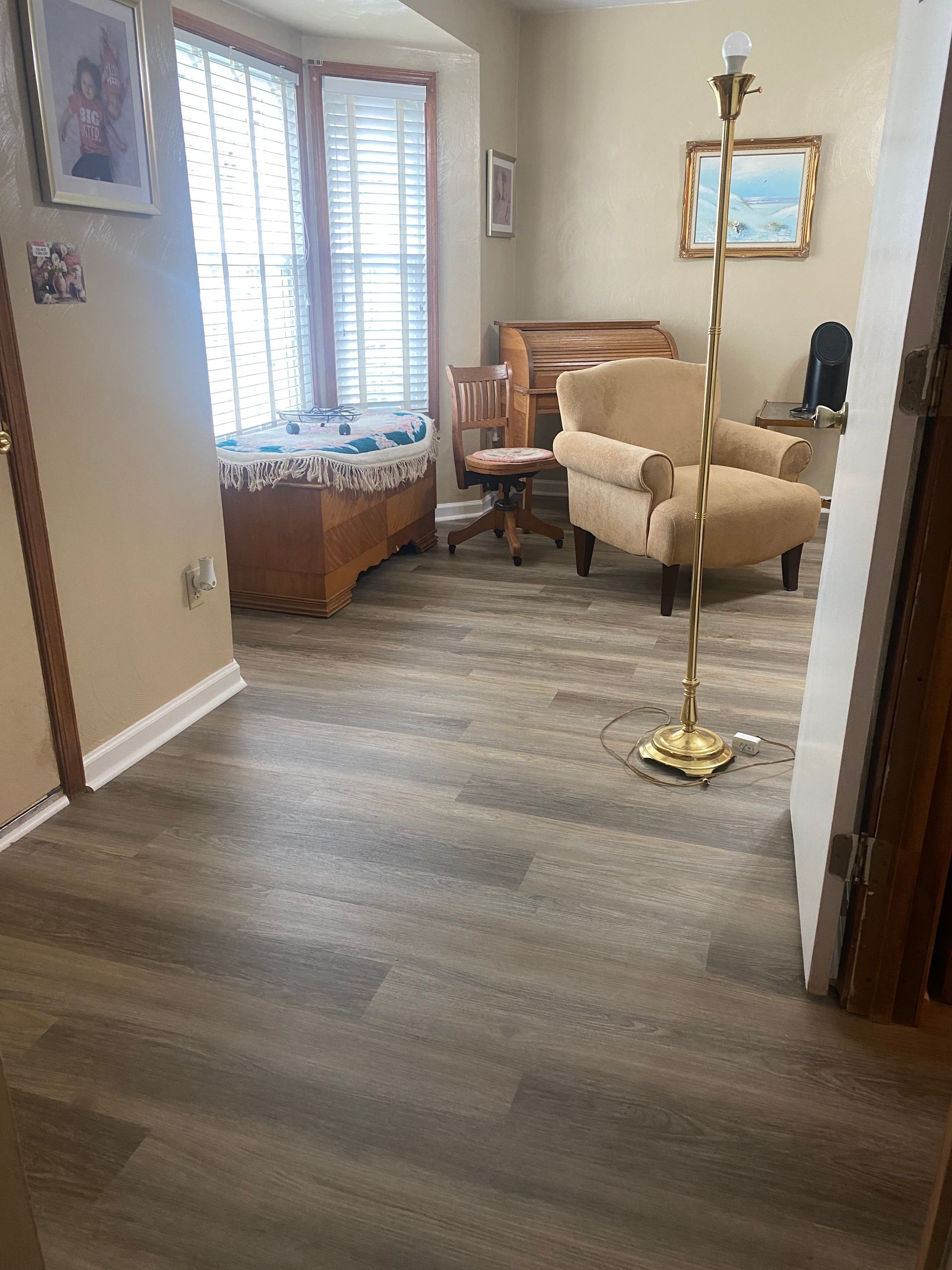 A living room with hardwood floors , a chair and a lamp.