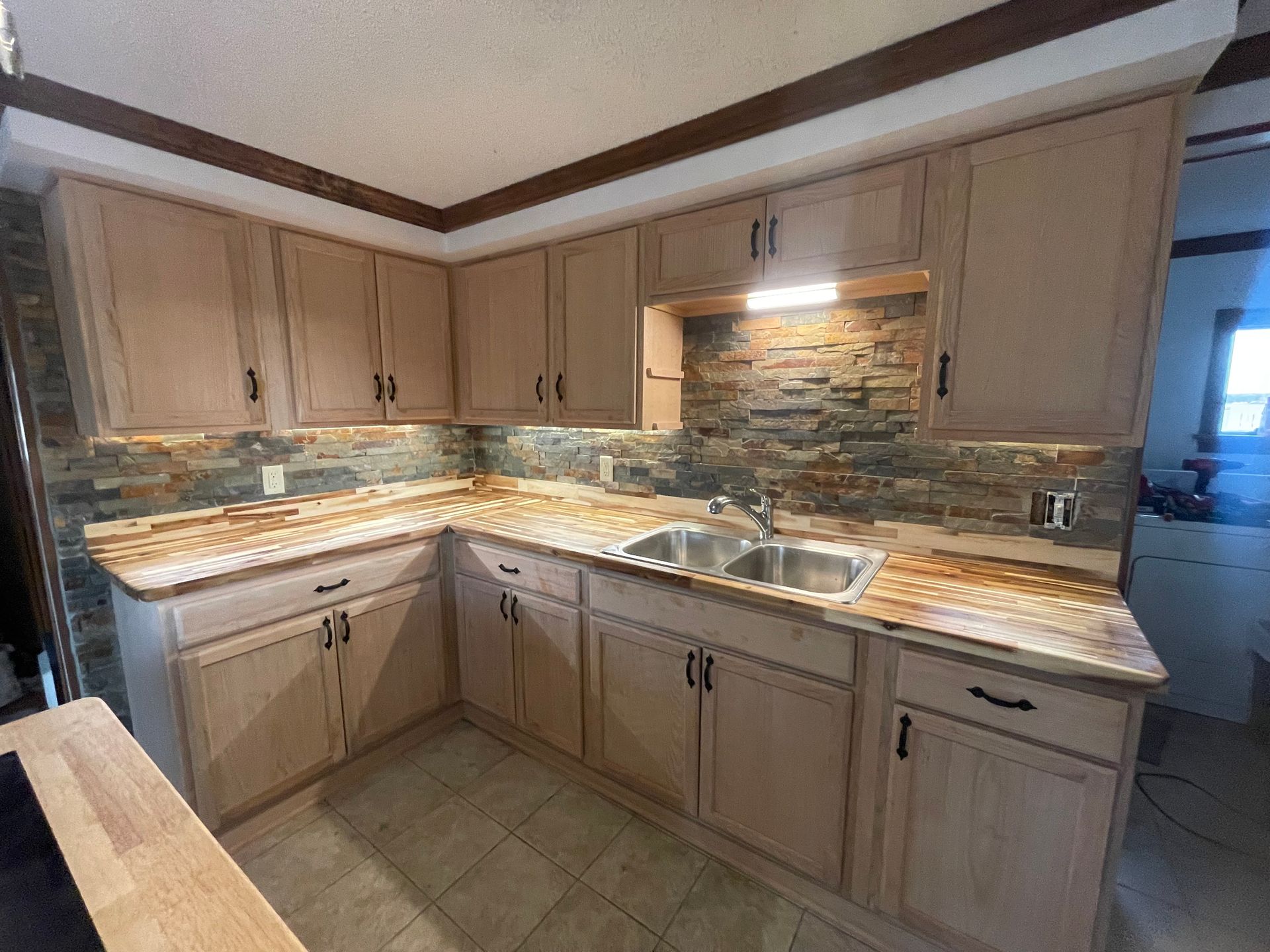 A kitchen with two sinks , wooden cabinets and granite counter tops.
