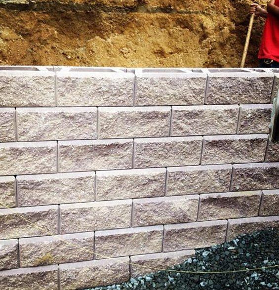 A man is holding a shovel in front of a brick wall.