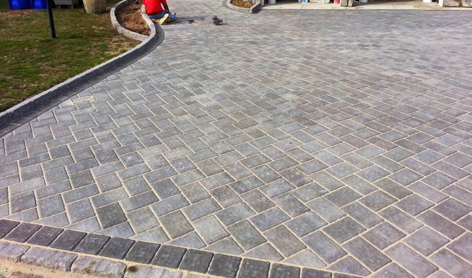 A brick driveway is being built in a herringbone pattern