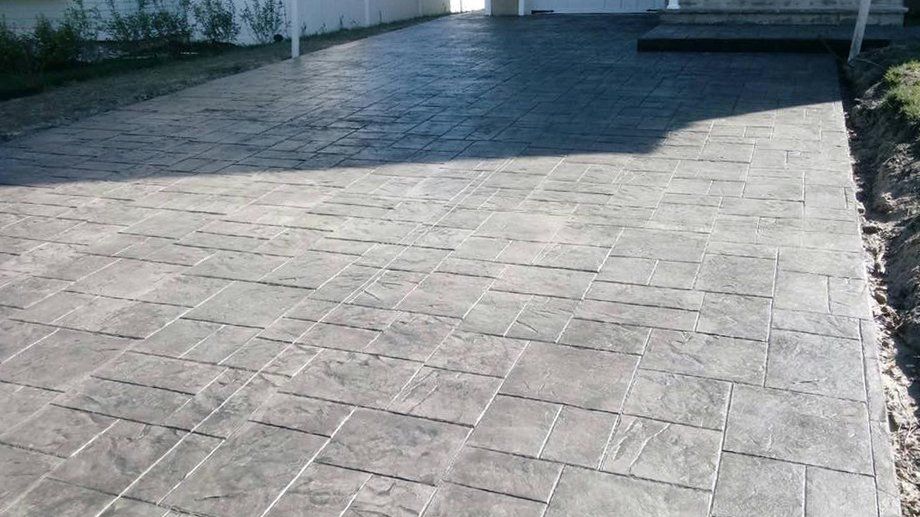 A gray brick driveway leading to a house.