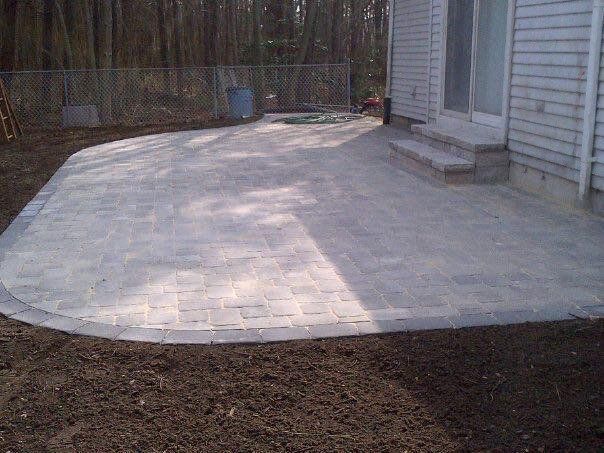 A patio is being built in the backyard of a house.