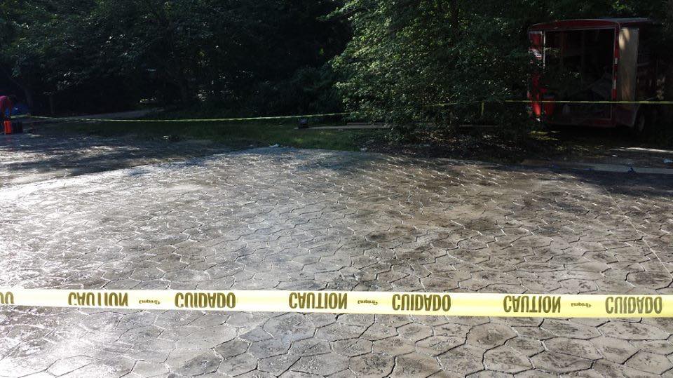 A concrete driveway with a yellow tape that says caution