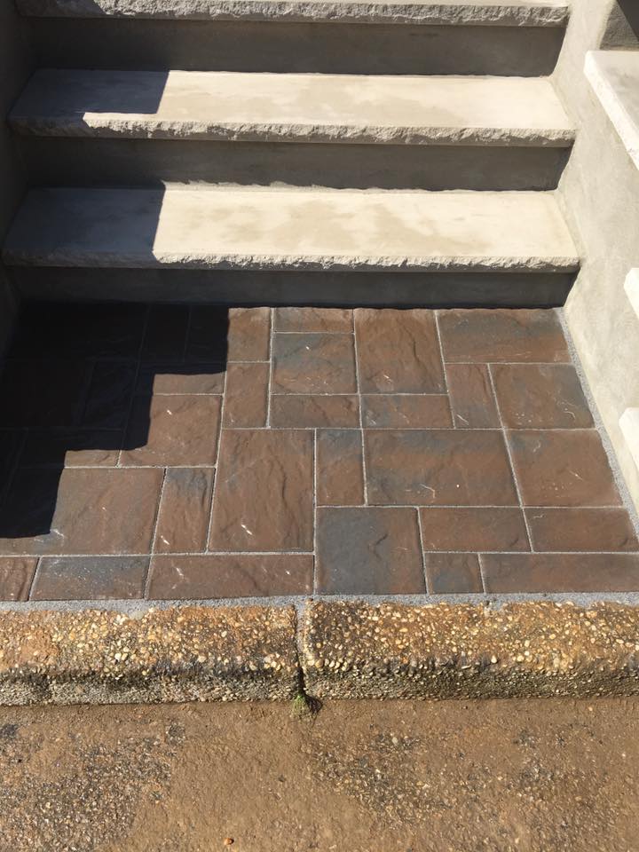 A set of stairs with a brick walkway leading up to them.