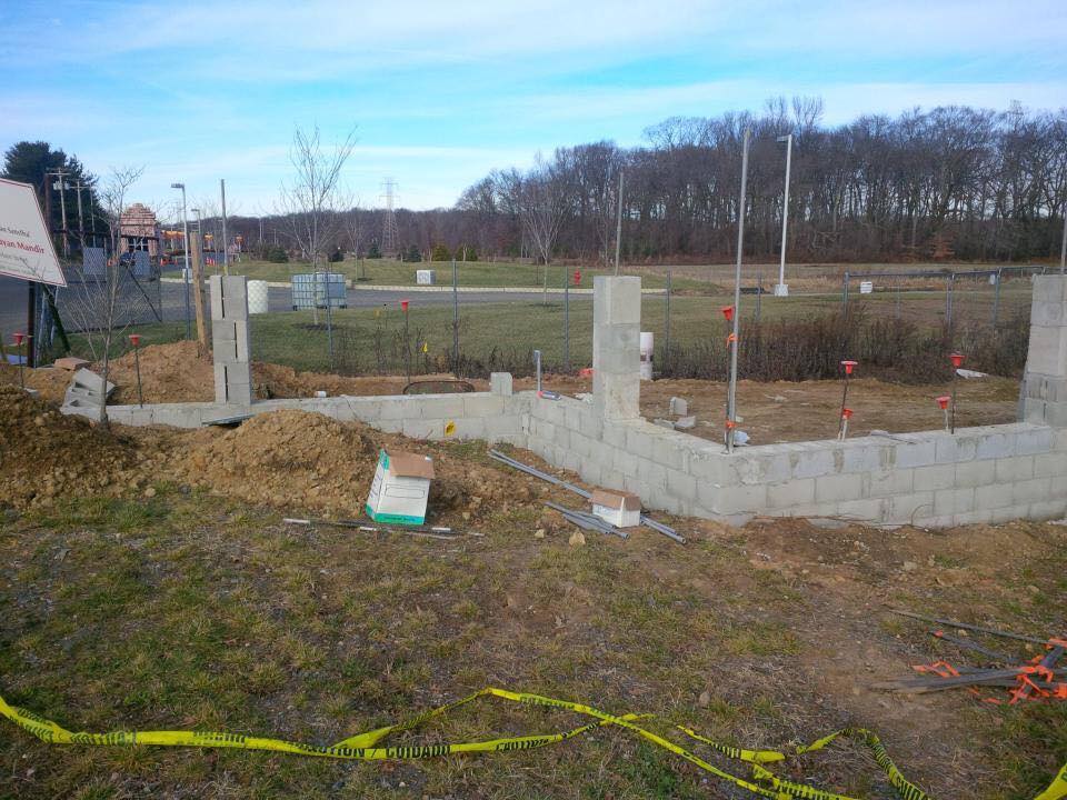 A brick wall is being built in the middle of a field.