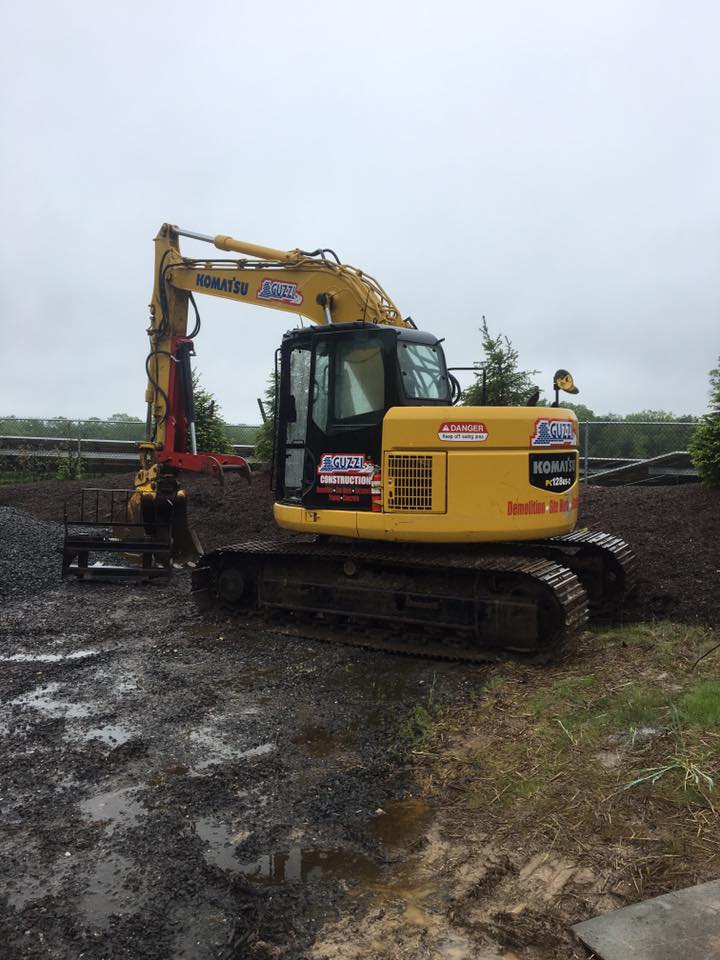 A yellow excavator is parked in a muddy field.