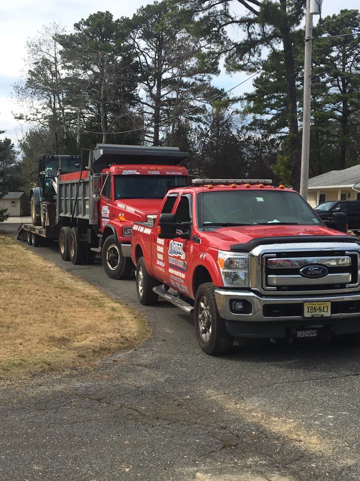 Two red trucks are parked on the side of the road.