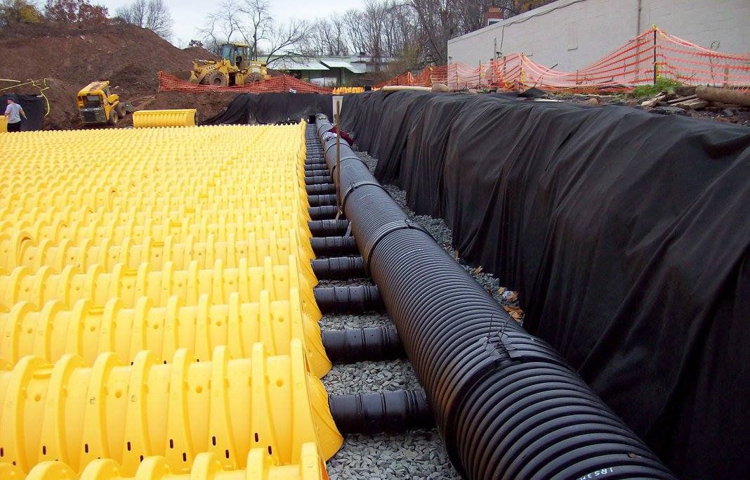 A bunch of pipes are laying on top of each other on a construction site.