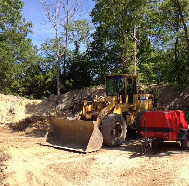 A bulldozer is parked in a dirt area with trees in the background
