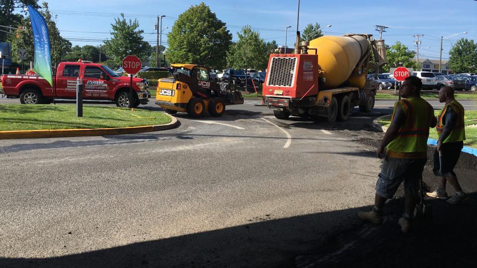 A group of construction workers are working in a parking lot.