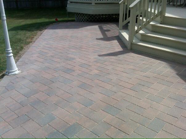 A brick walkway with stairs leading up to a deck