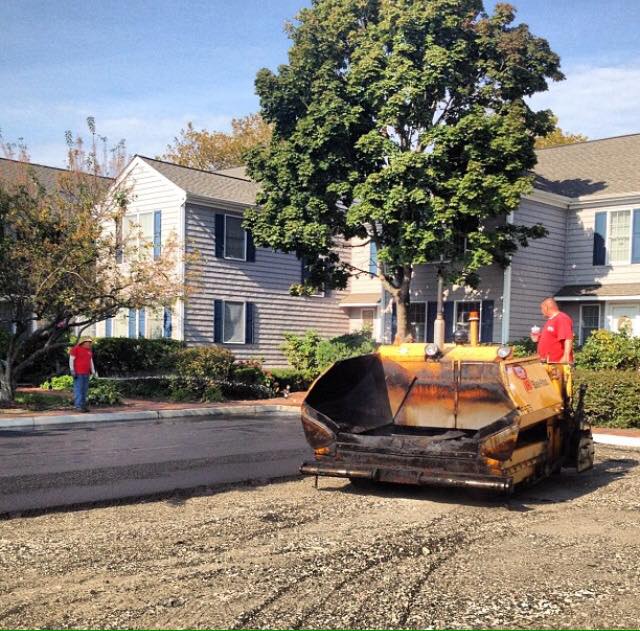 A man in a red shirt is standing next to a yellow tractor