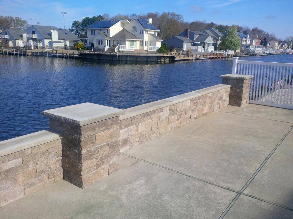 A brick wall overlooking a body of water with houses in the background