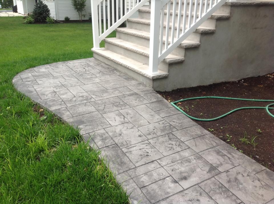 A walkway leading to a deck with stairs and a green hose