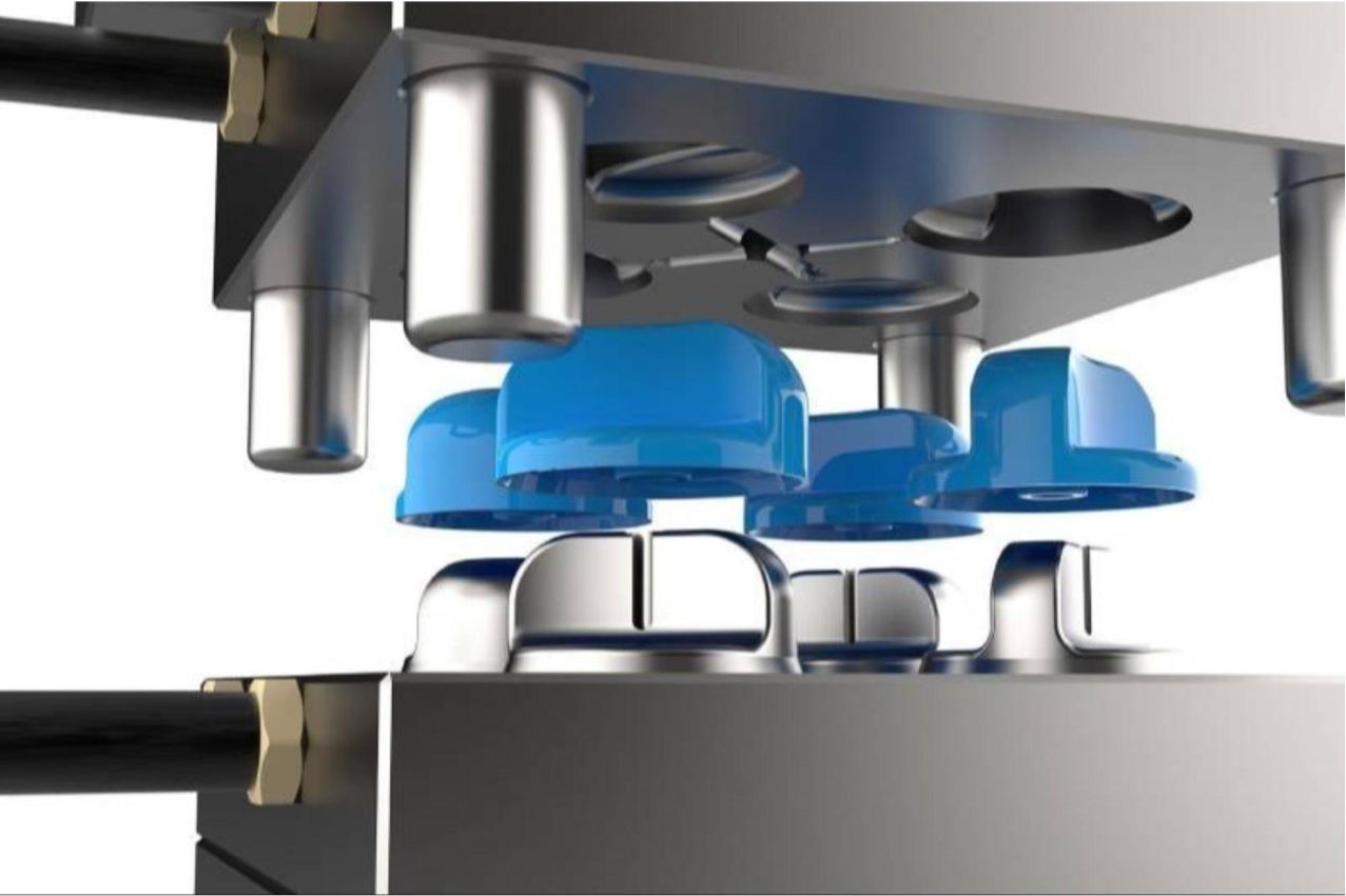 Blue plastic bottle caps being pressed by machinery.