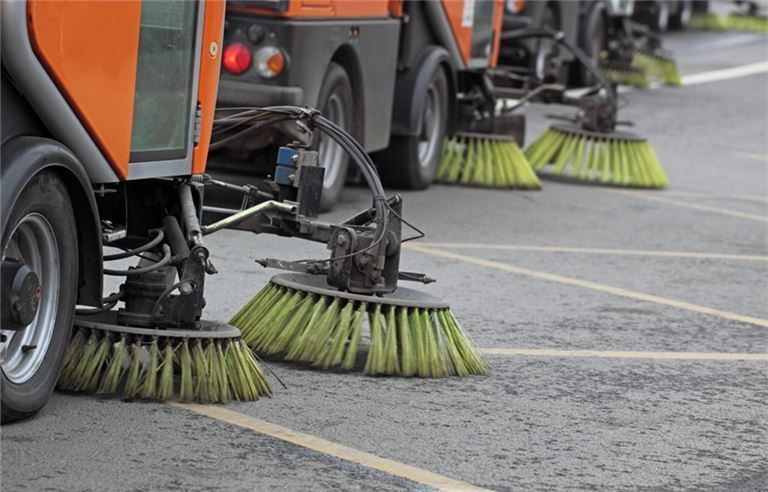 a row of street sweepers are lined up in a parking lot