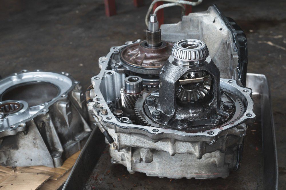 Open car transmission case with exposed gears and metal parts on a workbench