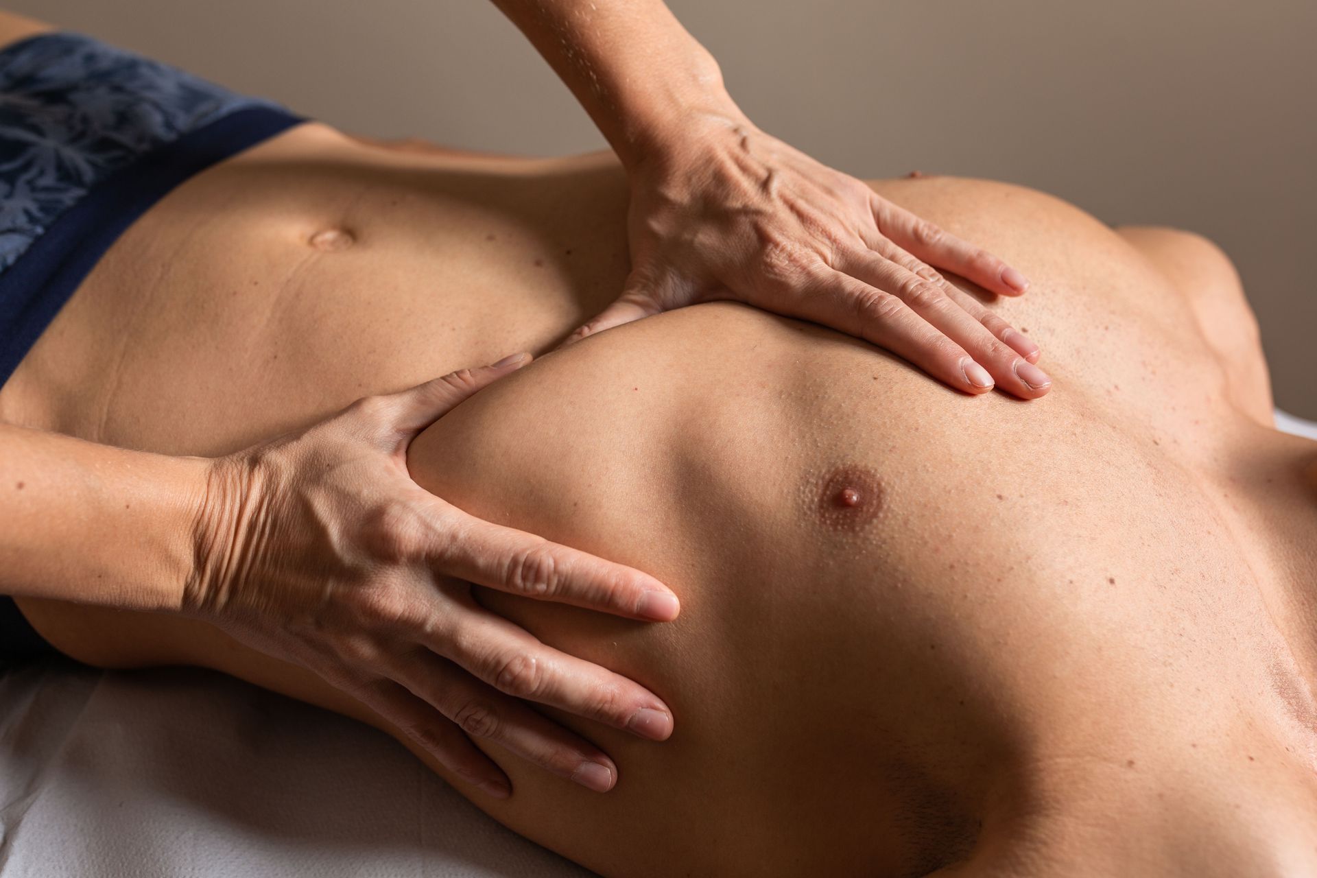 A woman is giving a man a massage on his chest.
