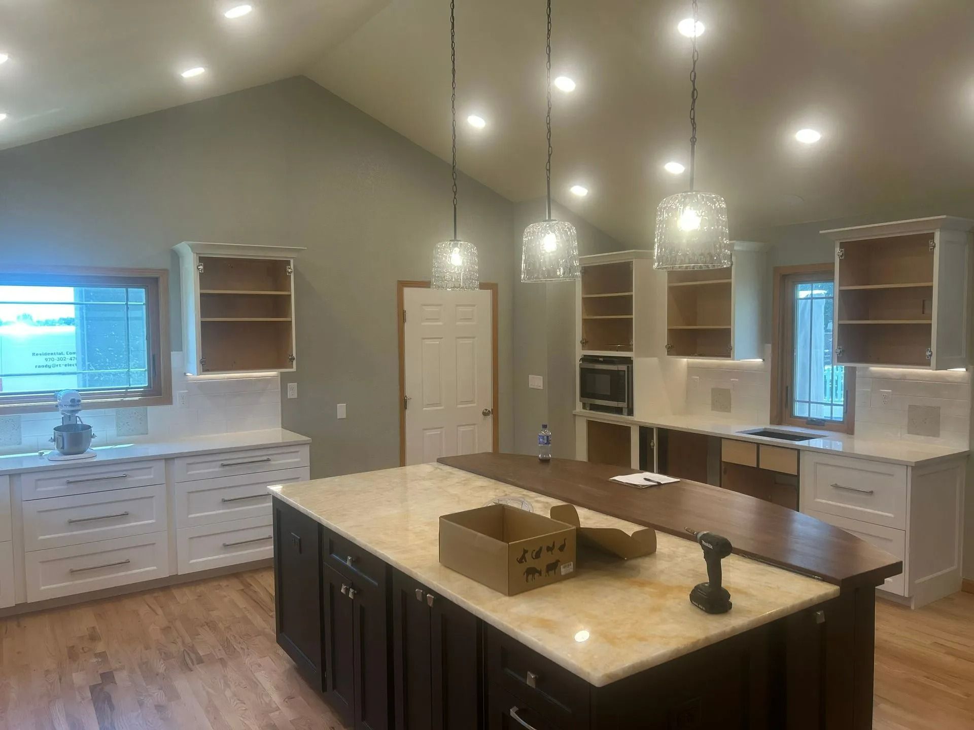 Kitchen with white and dark cabinets, island, wood countertops, and pendant lights.