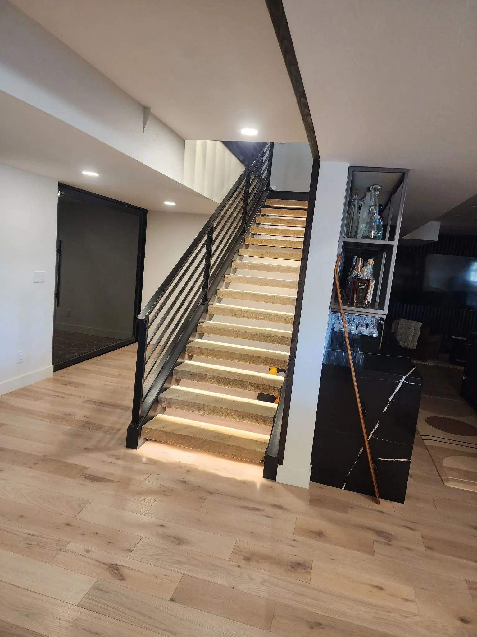 Wooden staircase with black metal railing, leading upwards. Well-lit interior.
