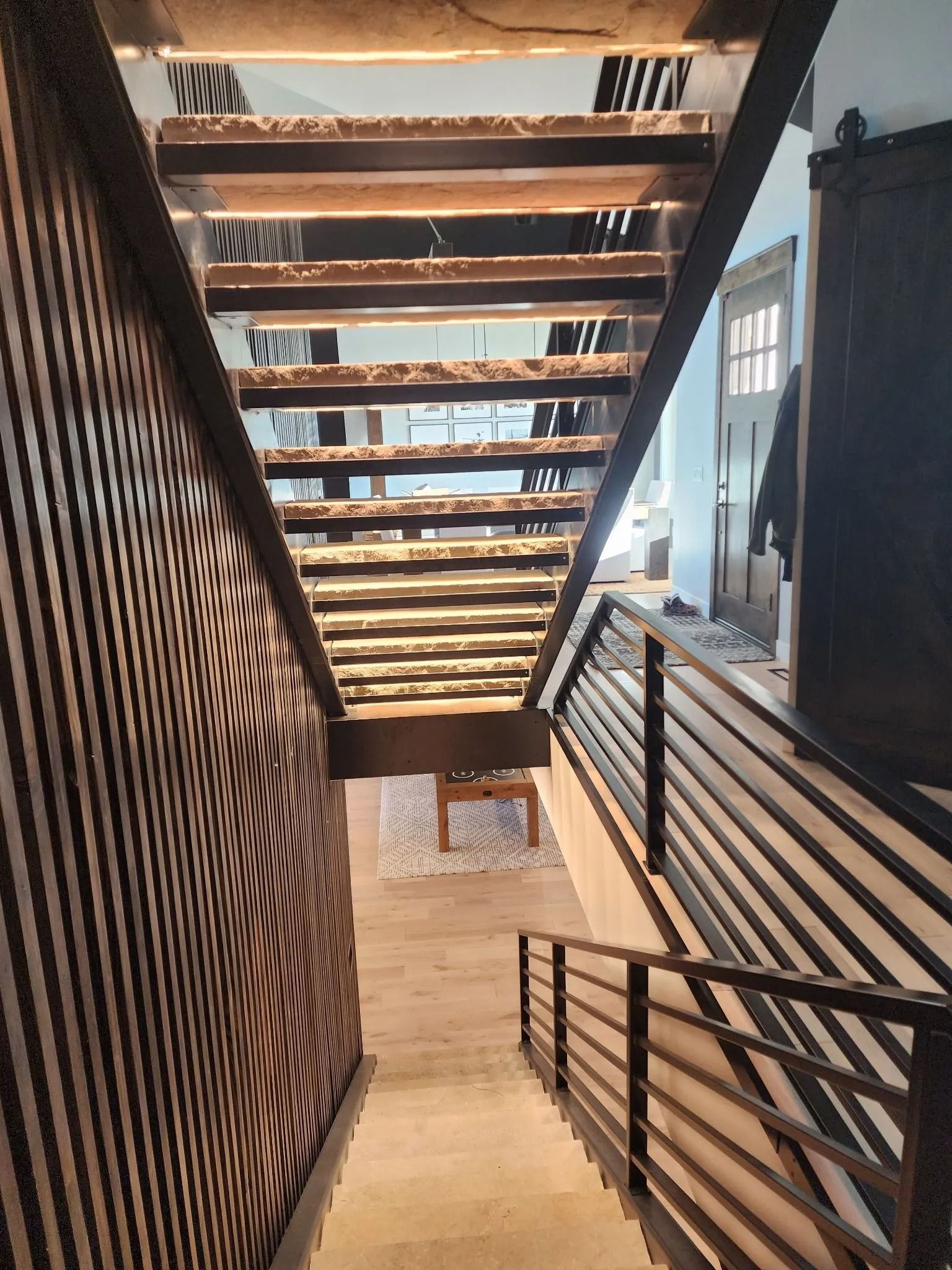 Staircase with wooden steps and railing. Dark wood panel wall on left. Metal railing on the right.