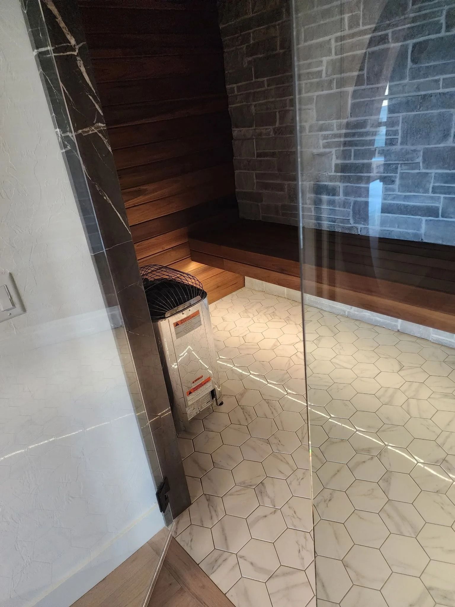 Interior view of a sauna with wooden benches, a heater, and stone walls.