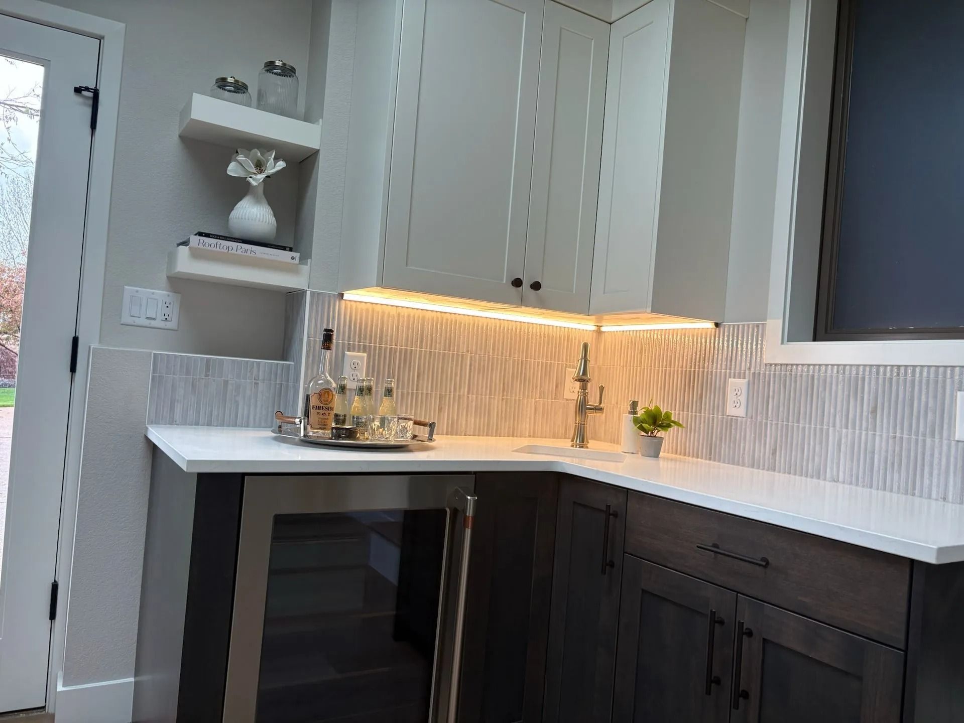 Corner bar area with white cabinets, stone backsplash, under-cabinet lighting, and a wine fridge.