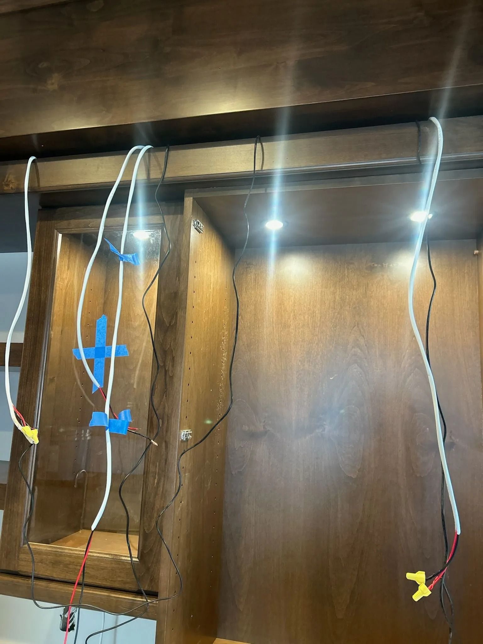 Wooden cabinet with LED lights and exposed wiring, secured with blue tape.
